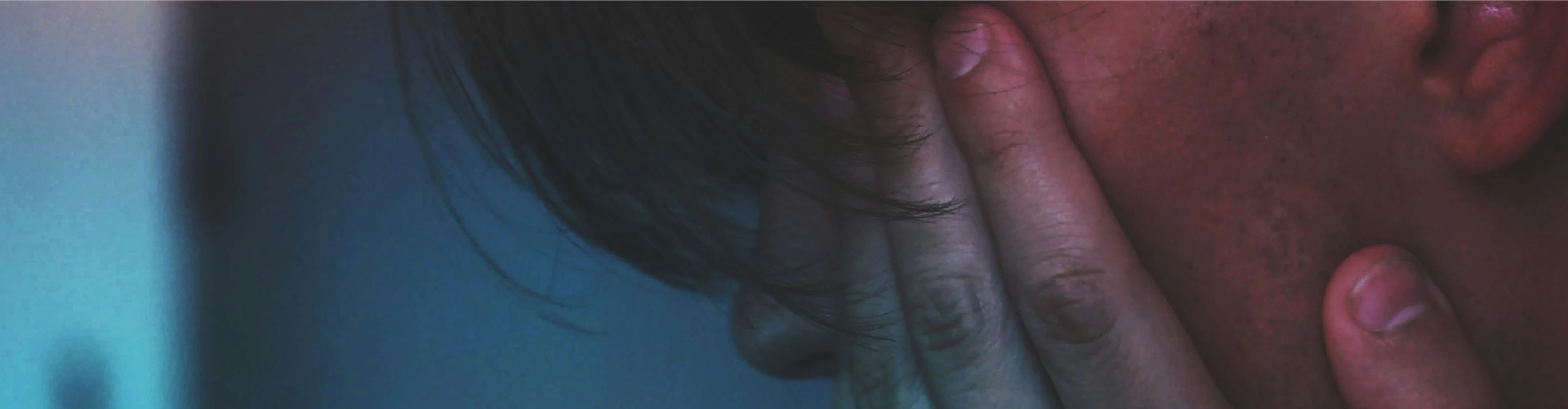 Mand som sidder i et dunket lokale med hænderne foran ansigtet